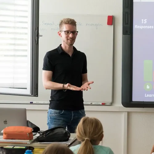 certified-teacher-english-language-course-classroom A certified teacher addressing students in a classroom, representing expert instruction in an English language course.
